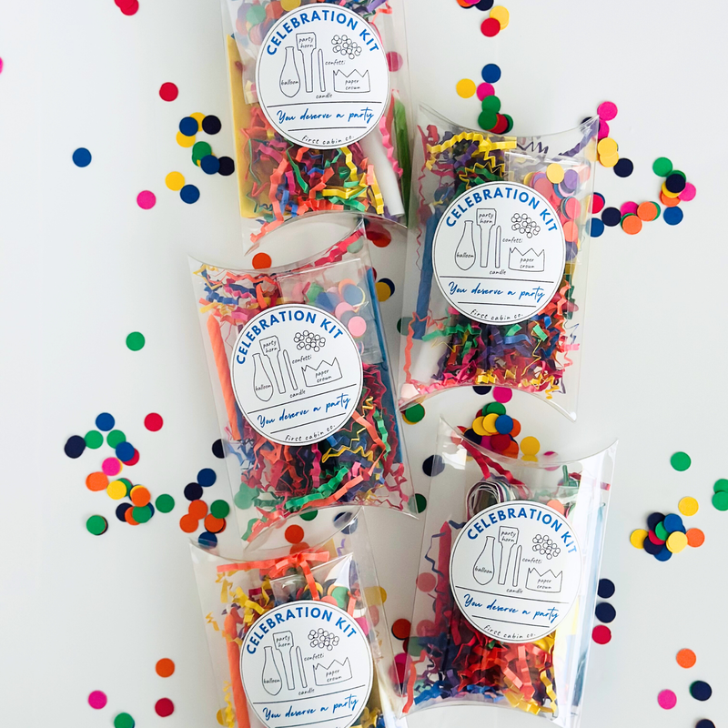 Five clear plastic boxes filled with colorful shredded paper party supplies and confetti, each labeled 'CELEBRATION KIT You deserve a party,' arranged on a white background with scattered multicolored confetti.