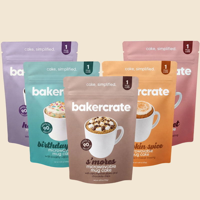 Five bakercrate mug cake pouches fanned out, s'mores in front with birthday cake, pumpkin spice, hot cocoa and red velvet behind