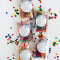 Five clear plastic boxes filled with colorful shredded paper party supplies and confetti, each labeled 'CELEBRATION KIT You deserve a party,' arranged on a white background with scattered multicolored confetti.
