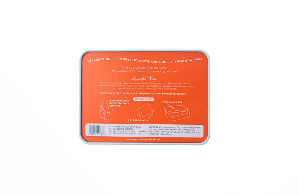 Back of the orange Emergency Confetti tin listing the kit contents: two poppers with biodegradable confetti, two clean-up aids, and one reusable tin