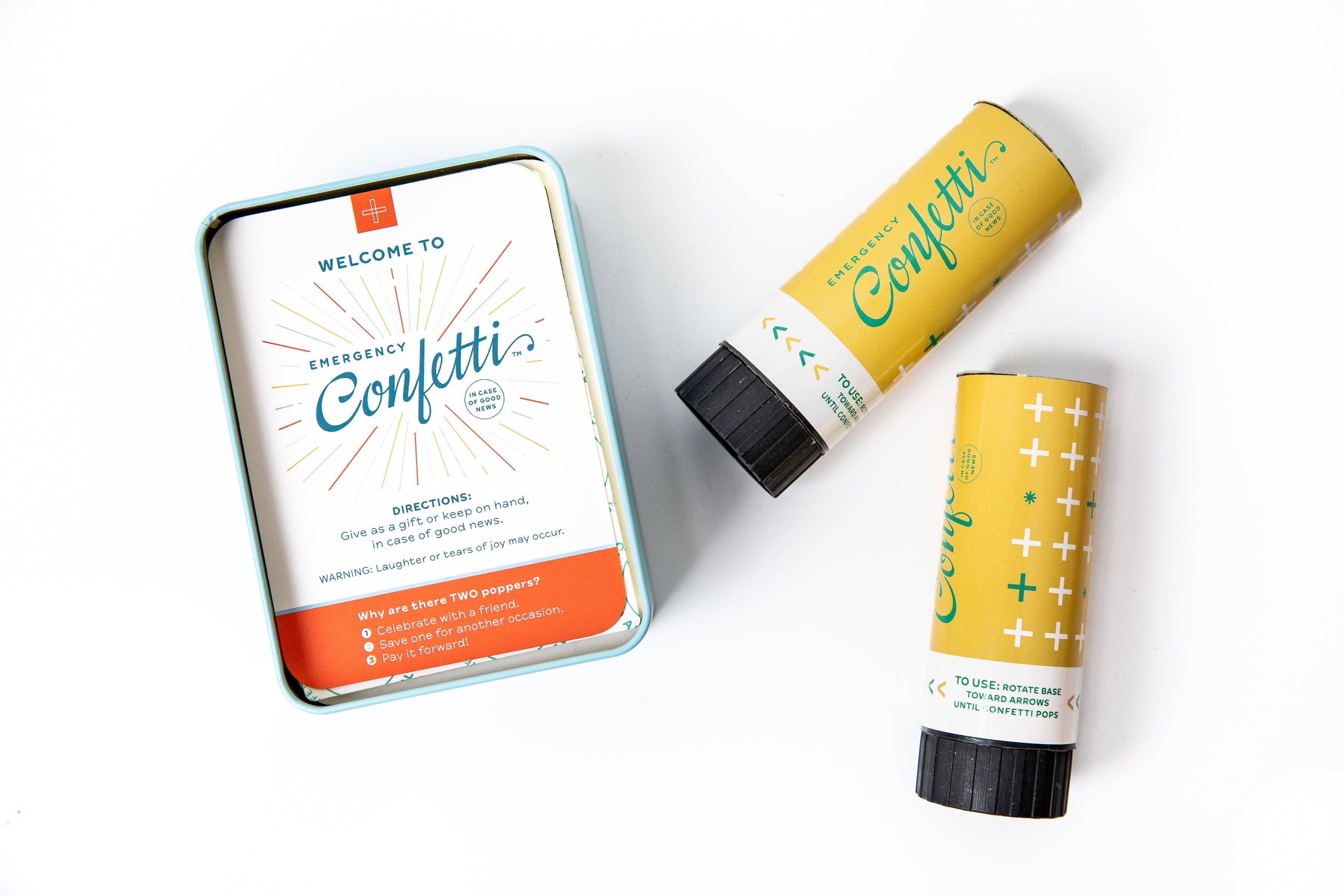 Open Emergency Confetti tin showing the printed directions card beside two yellow confetti poppers on a white background