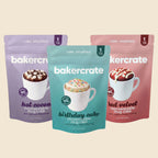 Three Bakercrate mug cake pouches in hot cocoa, birthday cake, and red velvet flavors
