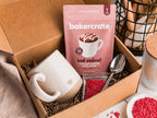 Bakercrate red velvet baking kit with a mug and ingredients in a cardboard box.