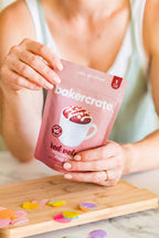Hands holding a Bakercrate red velvet mug cake mix pouch with candy confetti