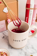 Gold mini wire whisk stirring red velvet mug cake batter in a Love You mug