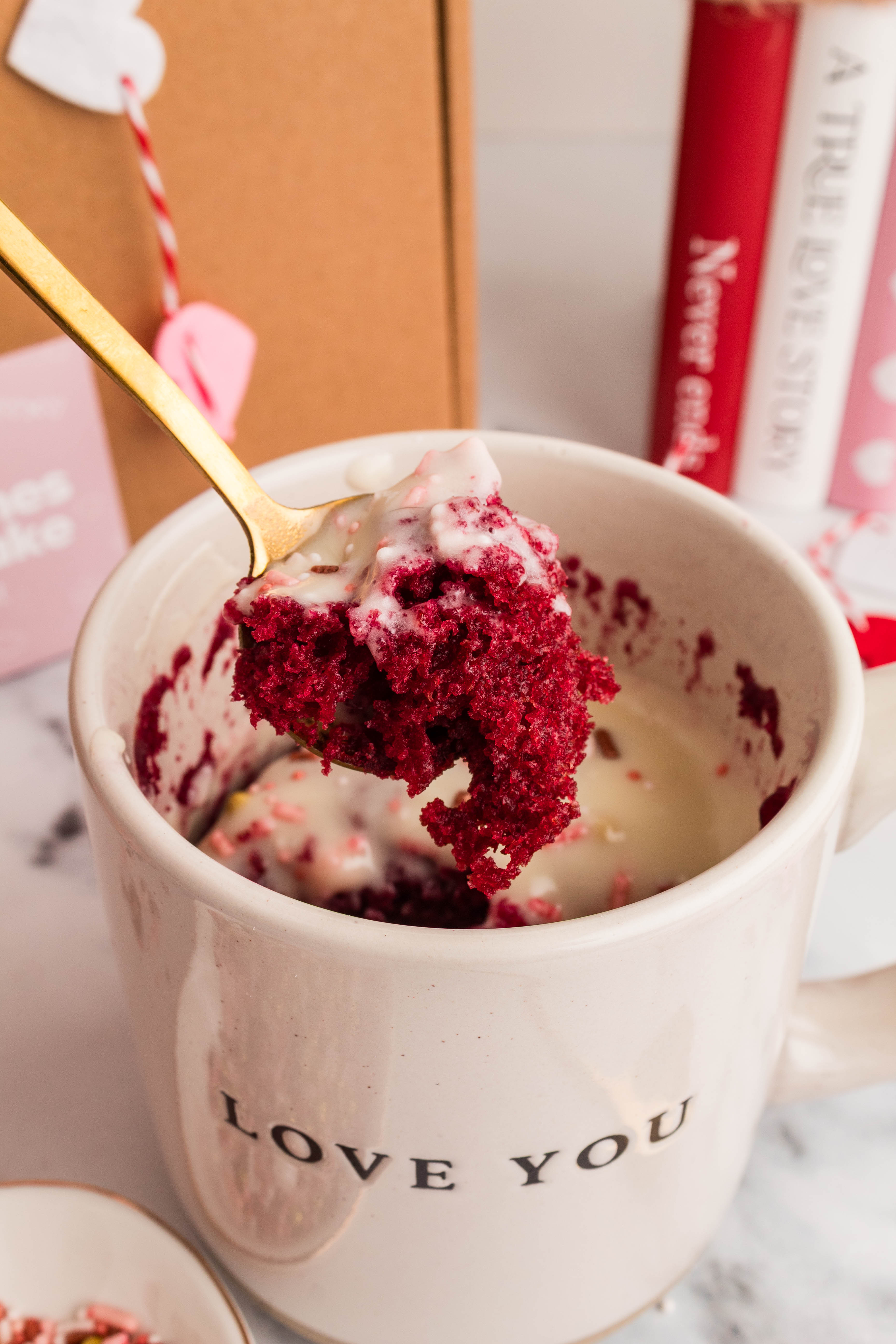 Red velvet mug cake in a Love You mug with a gold spoon and Valentine's Day styling